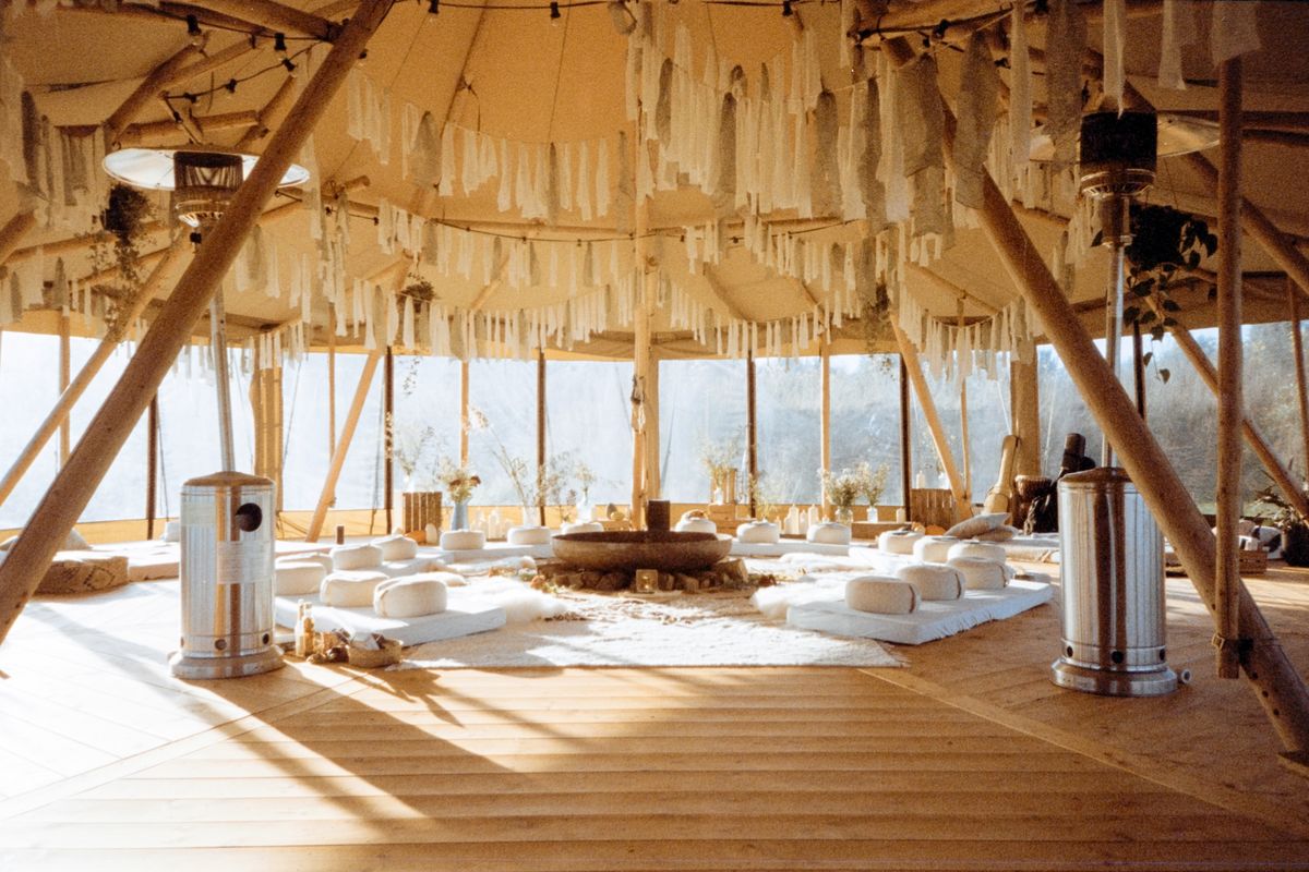 A wooden dome with cushions in a circle and tall windows open to the fields.